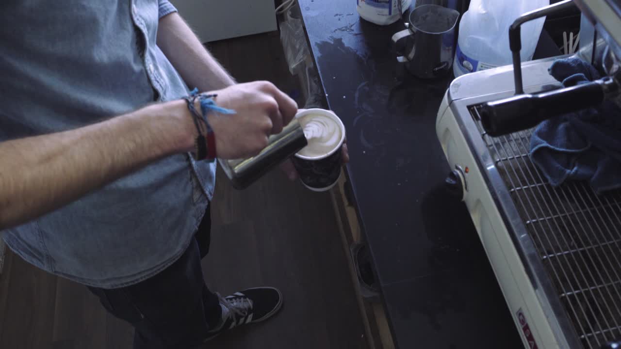 High angle pouring hot milk into cup of coffee, latte art