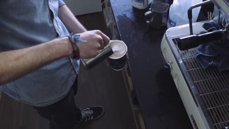 high angle pouring hot milk into cup of coffee, latte art