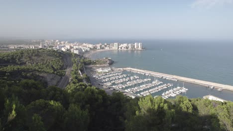 4k aerial view approaching oropesa del mar sail sport port and the scenic view of the touristic beach by the mediterranean sea, spain