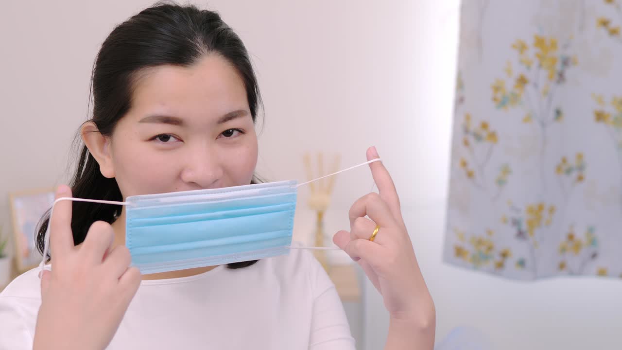 hermosa mujer asiática con una cámara con aspecto de máscara y estancia relajante en la cama en casa estilo de vida y concepto de placer