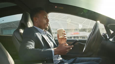 businessman in a car with coffee and phone