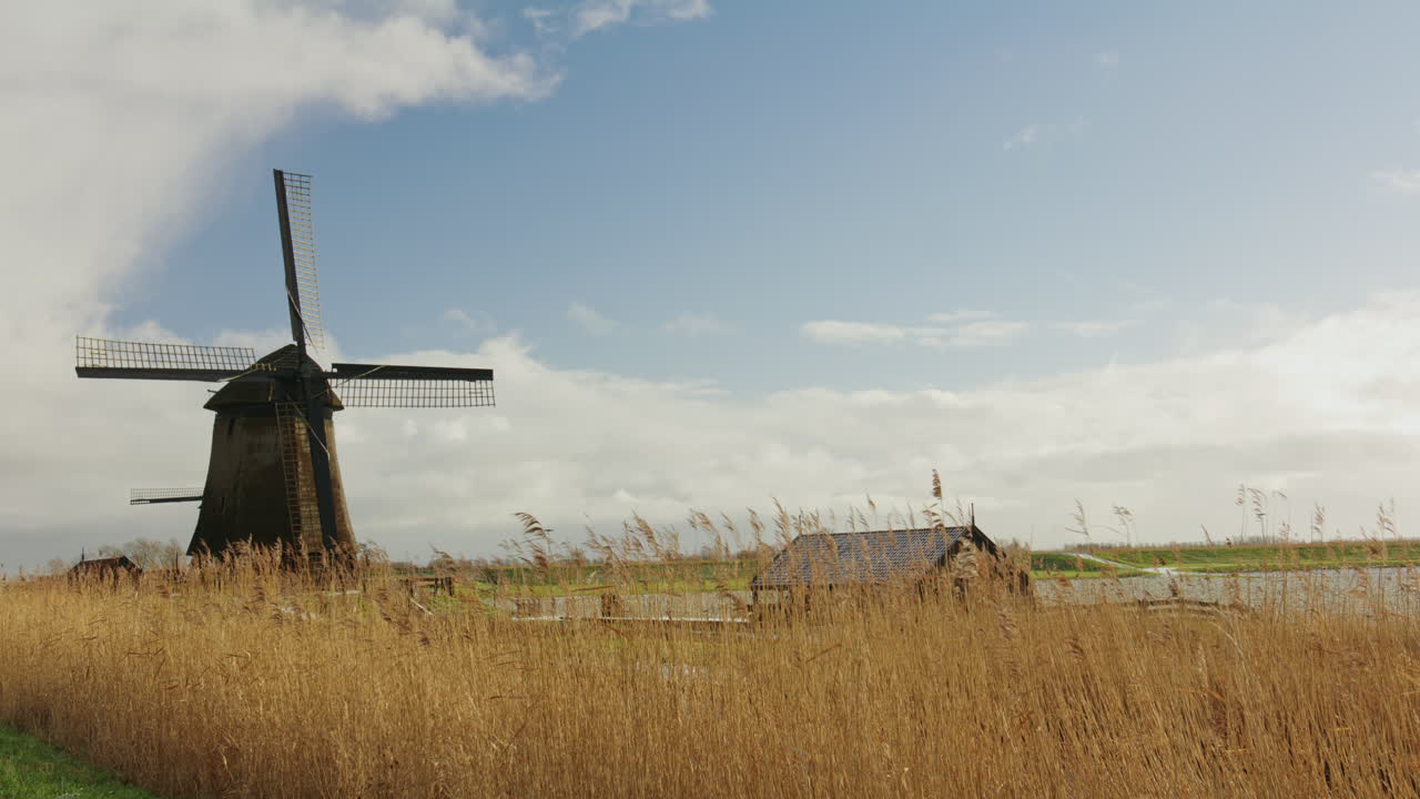 Laaja maaseutumaisema, jossa on historiallinen tuulimylly, jota ympäröivät ruo’ot ja avoin maaseutu leveän taivaan alla, sopii perintö-, maisema- ja rauhallisten maaseutukonseptien yhteyteen