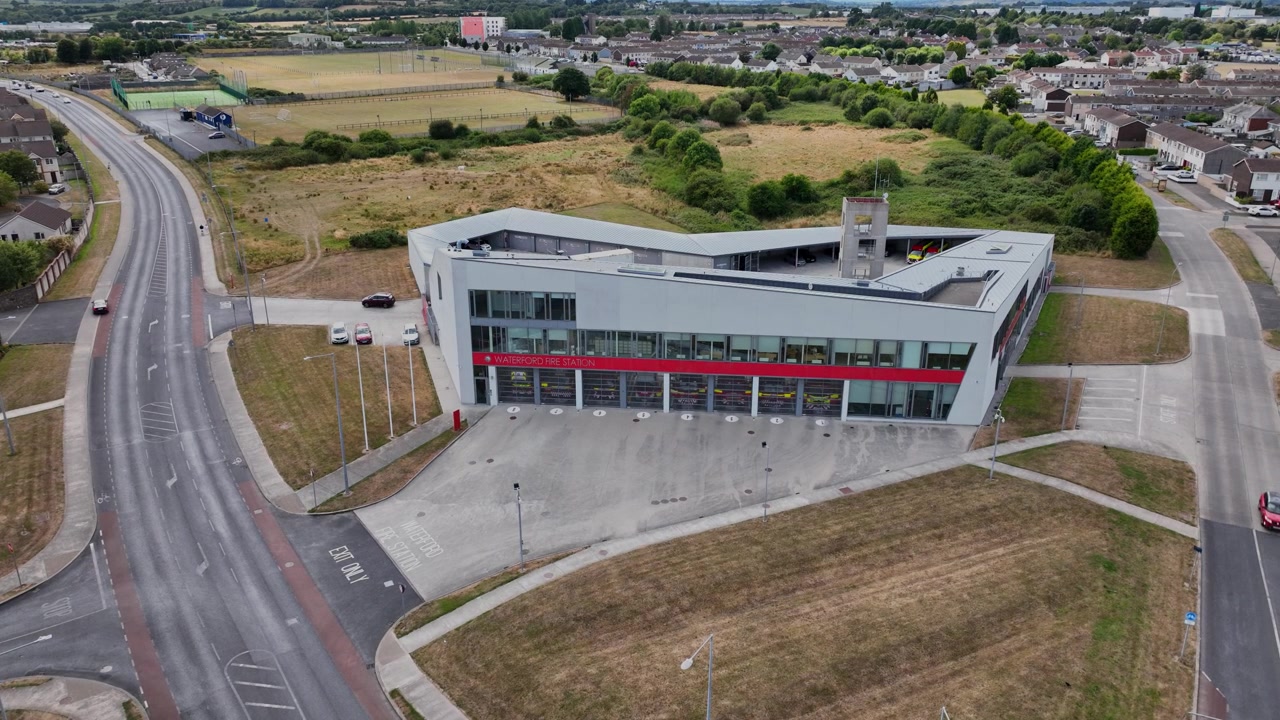 Bredt luftpanorama af Waterford City Brandstation i Irland, der afslører stationsområdet, det omkringliggende kvarter, vejnettet og byens skyline.