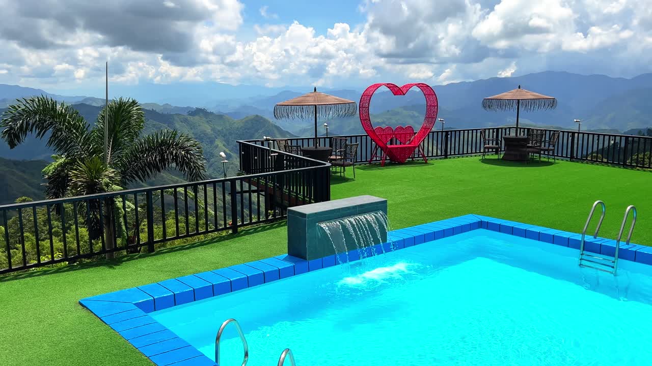 Luxury pool on mountain deck with heart sculpture, palm, and stunning views—ideal for romance, resorts, travel, and lifestyle content