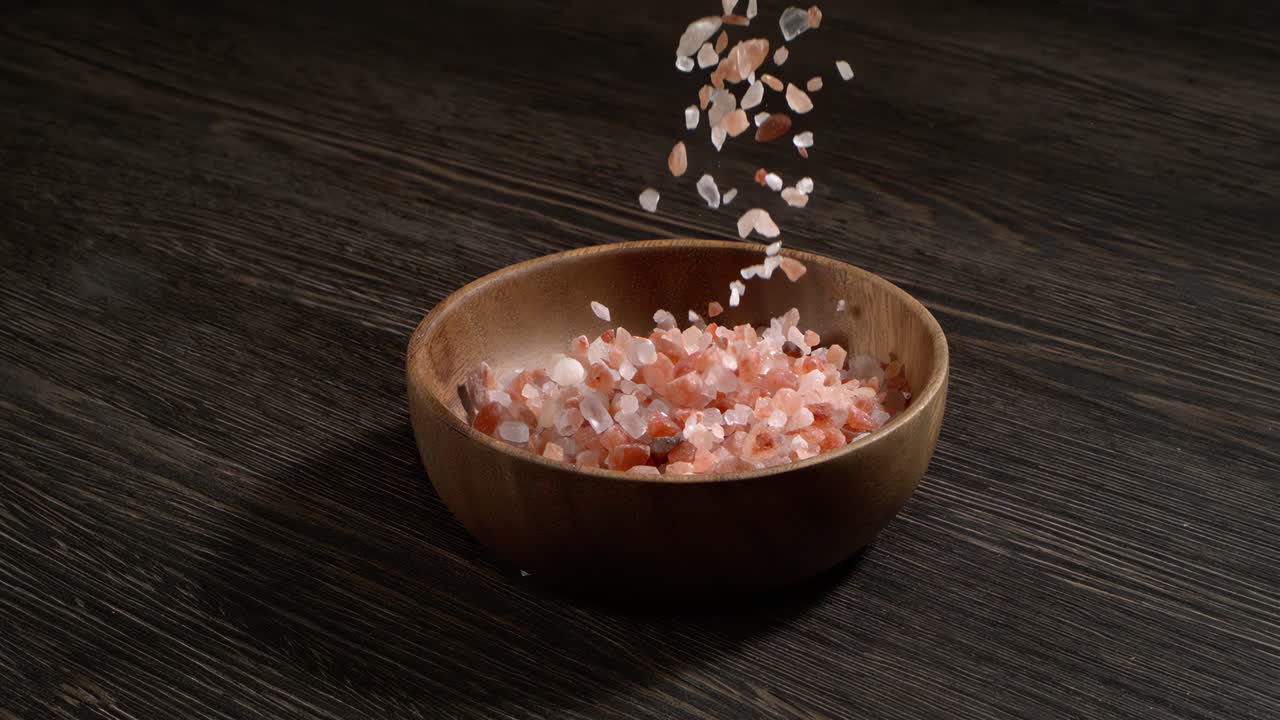Himalayisk pink salt i super slow motion, naturlig mineralsk krydderi til sund madlavning og spa-koncepter. Super slow motion 1500 fps