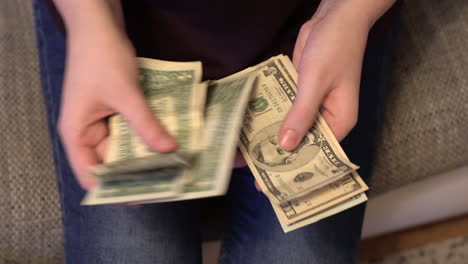 Top-view-shot-of-a-woman's-hands-counting-dollar-bills