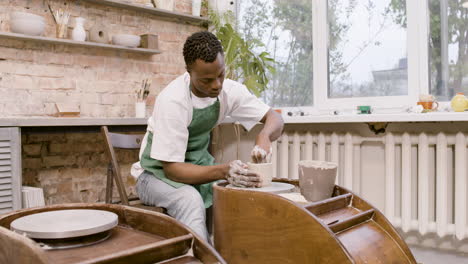 american man clerk modeling ceramic piece on a potter wheel in a workshop