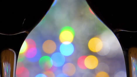 Extreme-close-up-Two-Red-Wine-glasses-in-foreground-on-colorful-bokeh-and-silver-blanket-close-up-in-a-romantic-intimate-atmosphere