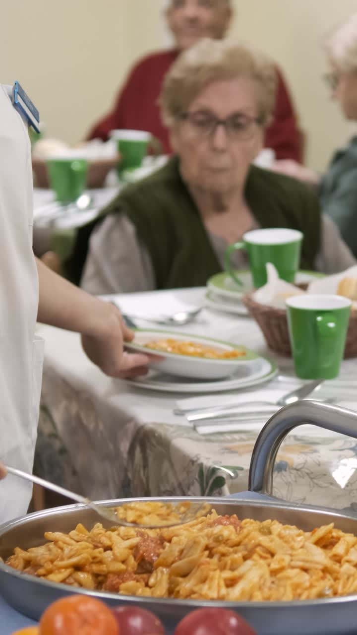 Crop worker serving pasta in plate for elderly people