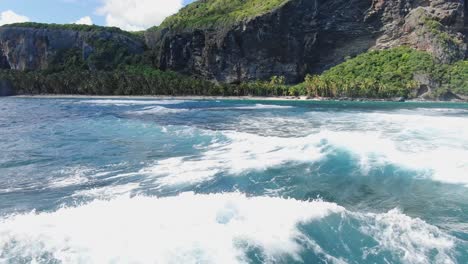 Aerial-flyover-wavy-Caribbean-Sea-with-Playa-Fronton-in-background-during-sunny-day---Samana,Dominican-Republic