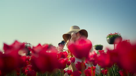 Pretty-female-flirting-among-red-flowers.-Happy-woman-in-love-sitting-in-garden.