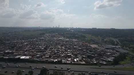 Push-in-drone-shot-glides-over-the-township-of-Alexandra-in-Johannesburg,-offering-a-glimpse-of-the-energetic-cityscape-and-rapid-transportation-in-motion