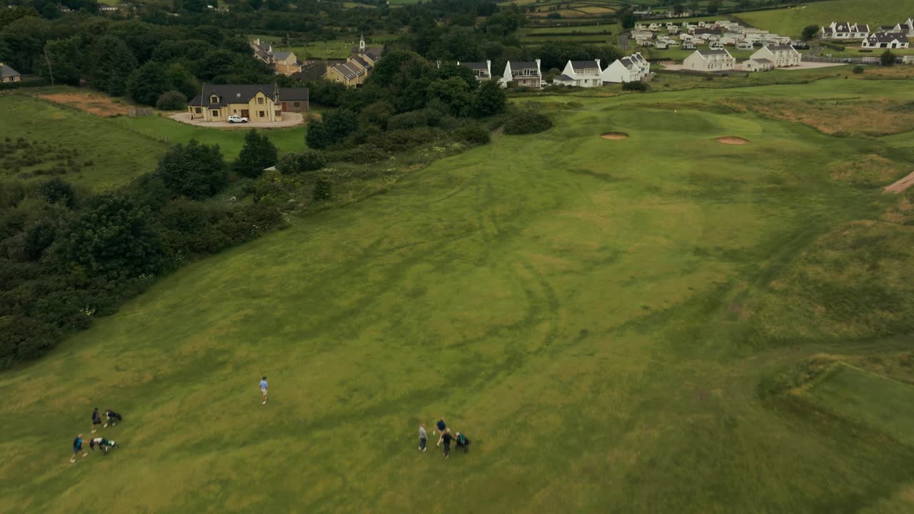 골퍼와 캐디가 아일랜드의 상징적인 아일랜드 링크스 골프 코스에서 플래그스틱을 향해 그린 페어웨이를 고 있는 드론 비행