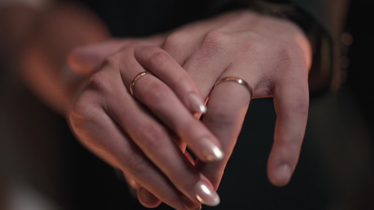 Close-Up of Couple Hands with Wedding Rings in Warm Romantic Lighting, Emotional Connection