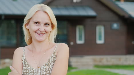 Portrait-Of-An-Attractive-Woman-On-The-Background-Of-Her-House-Looks-At-The-Camera-Smiling-Slow-Moti