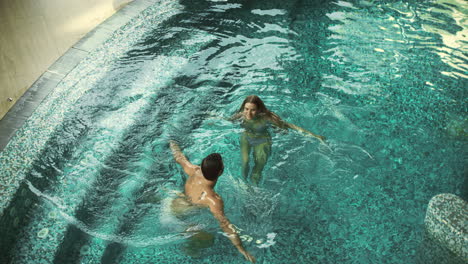 Top-view-of-cheerful-couple-in-pool-indoor.-Couple-having-fun-in-whirlpool-bath