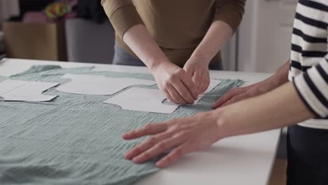 Two-seamstresses-working-with-a-cloth-and-a-chalk-on-a-table