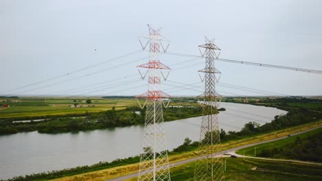 Aerial-pov-of-high-voltage-pylons-and-cables-with-Po-Italian-river-rural-landscape