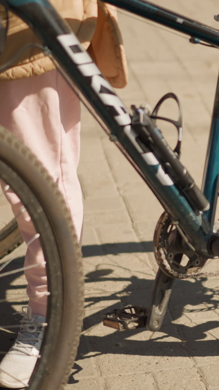 Close-up shot of bicycle with muddy tires on urban street, person standing with bike, casual outdoor lifestyle, city cycling, sunny day, biking gear, urban transportation