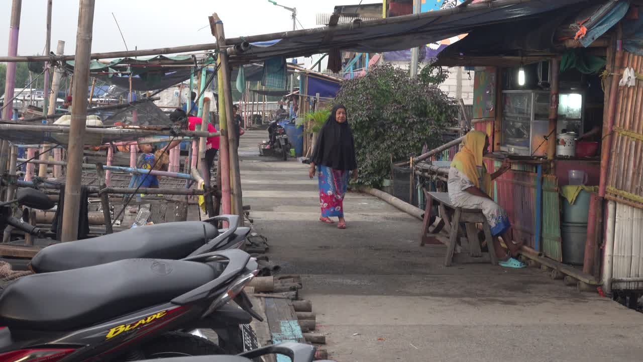 Pessoas caminhando em um movimentado caminho de aldeia asiática.