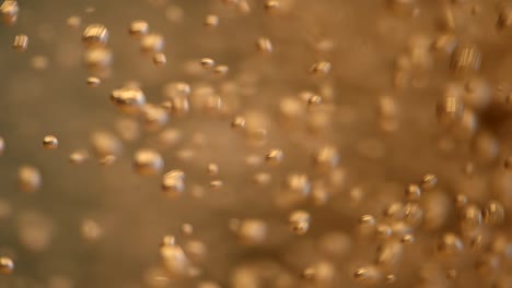 many bubbles fizzing in golden drink macro slowmotion