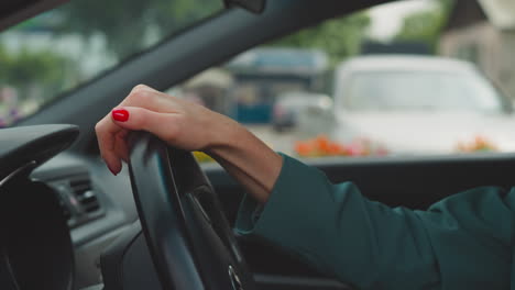 hands of woman with red nails turning steering wheel in car