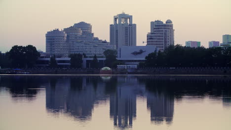 city skyline reflection on calm water at dawn/dusk