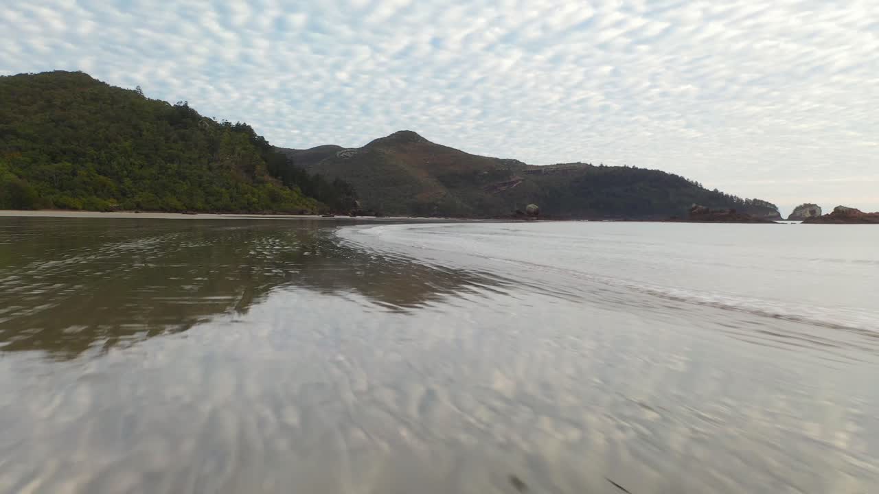 공중:해질녘에 호주의 넓은 젖은 모래 해변 위를 저속 비행