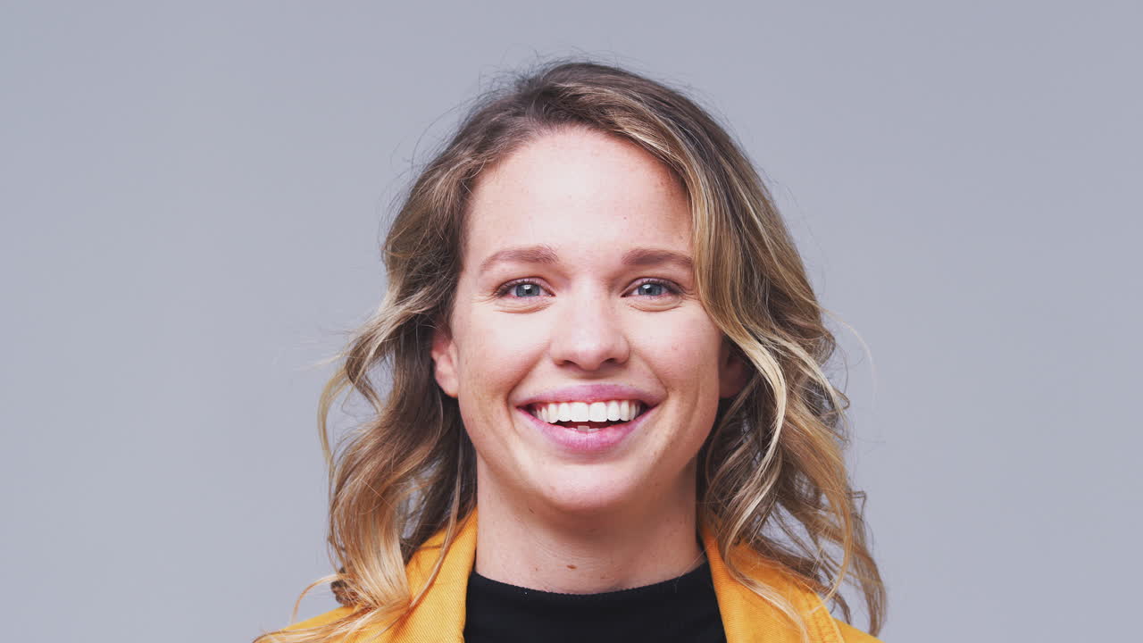 Close Up Head And Shoulders Studio Shot Of Woman Laughing At Camera In Slow Motion