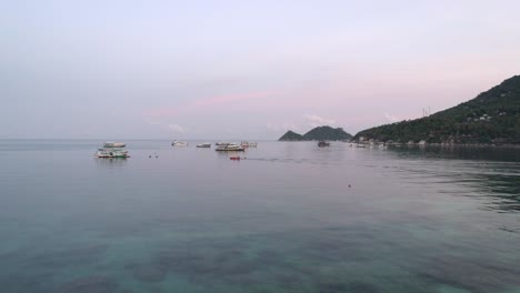 mar tranquilo con barcos y isla en el fondo