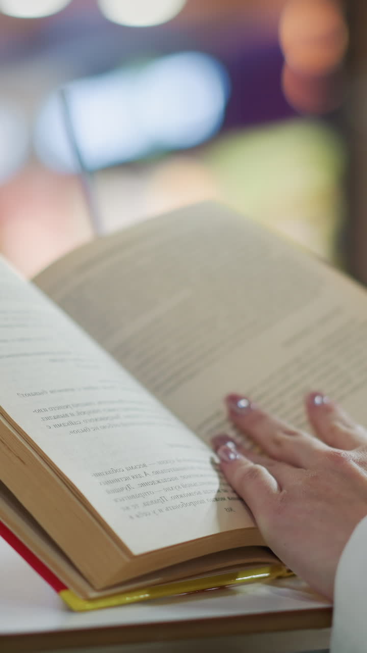 primer plano de manos volviendo las páginas de un libro abierto con un fondo borroso con luces suaves, creando una escena tranquila y reflexiva