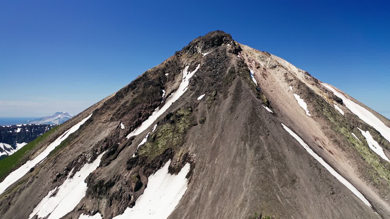 공중 파노라마. 빛의 은 파란 하늘 위에 눈이 내린 녹색 화산 정상