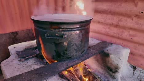 boiling water in a sooty pot over an open fire