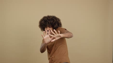 man with afro hair making a scared or defensive gesture