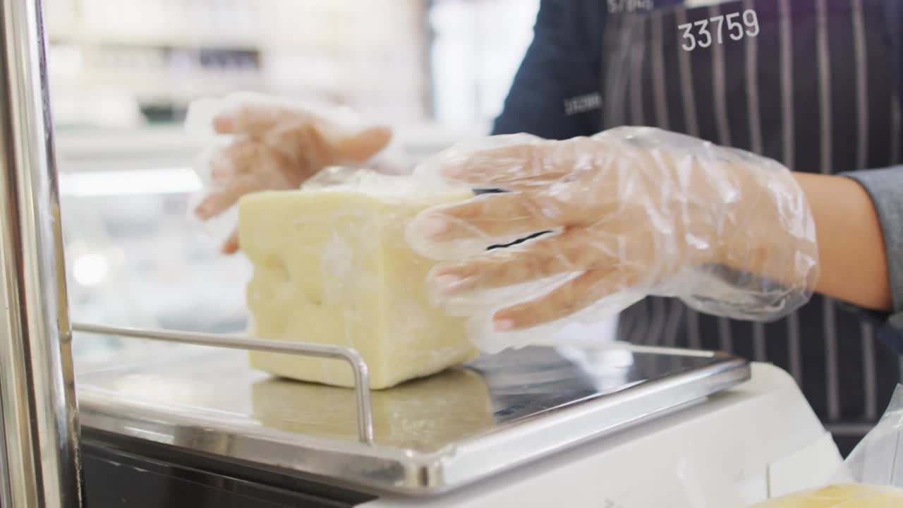 Gloved deli employee placing cheese onto scale platform and aligning center for accurate weighing