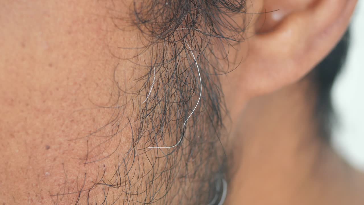 Close-up of a person touching gray hair near the ear