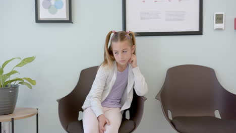 Bored-caucasian-girl-patient-sitting-waiting-in-hospital-reception,-copy-space,-slow-motion