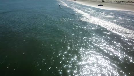 Luftdrohnenansicht,-Die-Sich-Einem-Fischer-Nähert,-Der-An-Einem-Sonnigen-Nachmittag-In-Der-Brandung-Am-Strand-Auf-Einer-Barriereinsel-An-Der-Golfküste-Steht---South-Padre-Island,-Texas