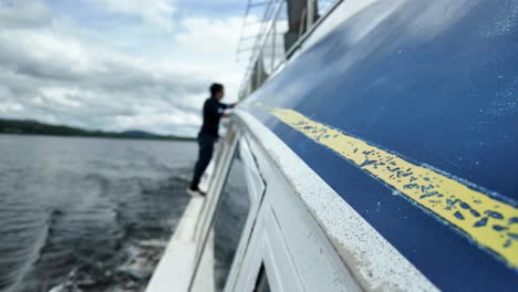 man walks along gunwale of steel boat