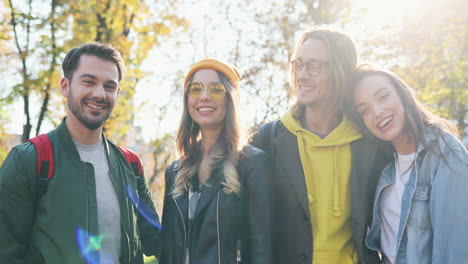 two happy caucasian young couples of friends smiling to the camera in the park in autumn