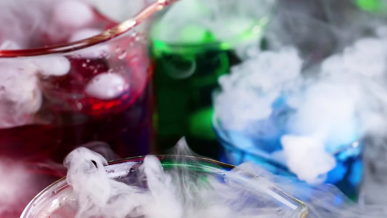 Close-up of colorful liquids reacting with vapor in laboratory beakers, showcasing dynamic chemical interactions.