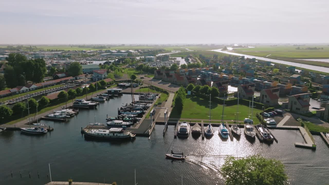 Drone performs a smooth pan left showcasing boats docked at Heeg marina and colorful waterfront buildings
