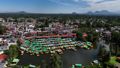 aerial view orbiting trajinera boats parked at the xochimilco lake, in sunny mexico