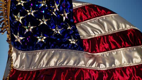 gemstone encrusted american flag billowing vigorously, sparkling intricately with luminous details against expansive blue sky backdrop