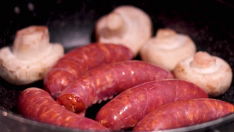 sausages and mushrooms cooking in a pan