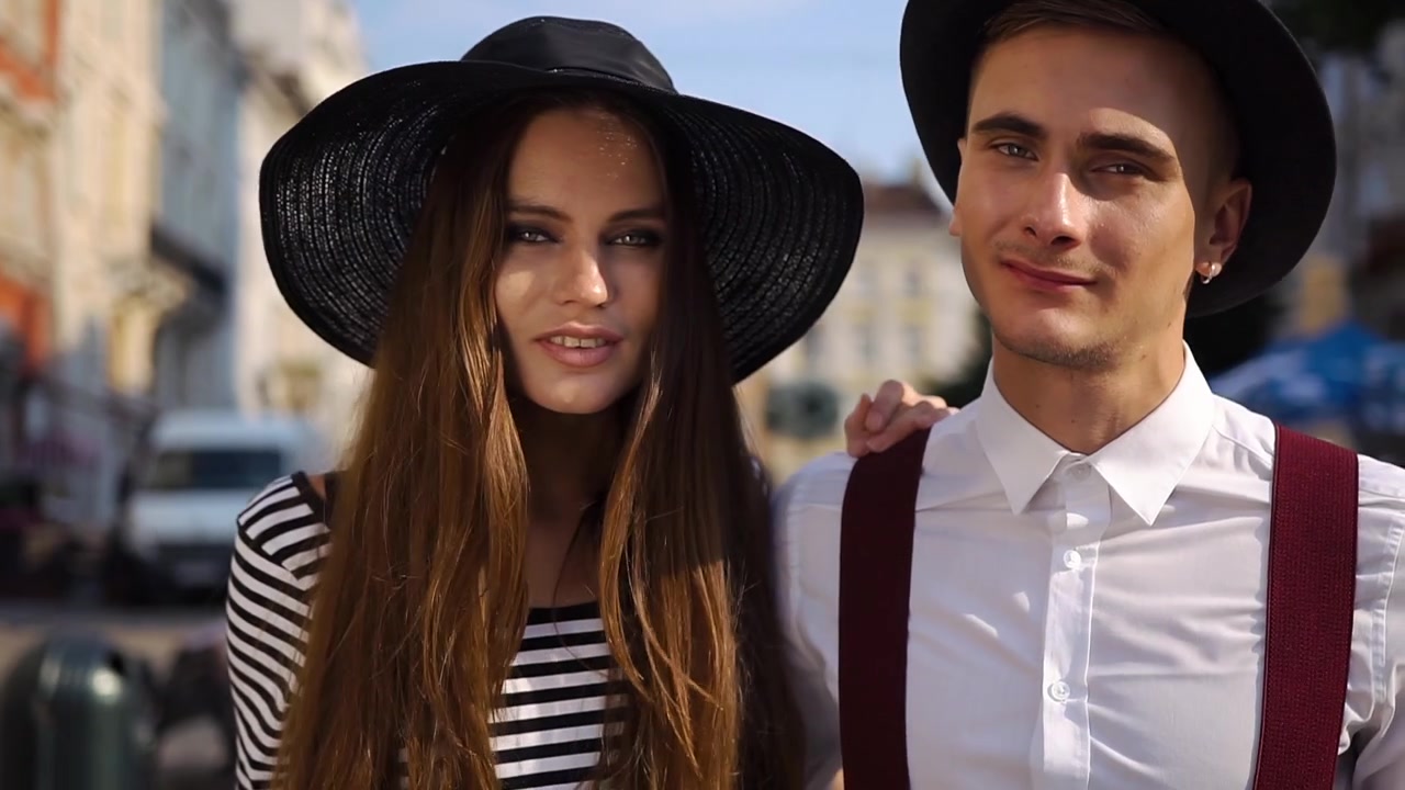 Giovane coppia elegante con cappelli che cammina insieme in città