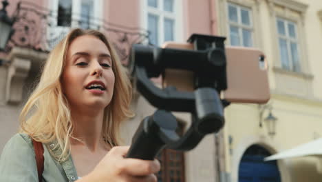 feliz bloguera de viajes contando algo mientras graba un video en el smartphone con un selfie stick en la ciudad