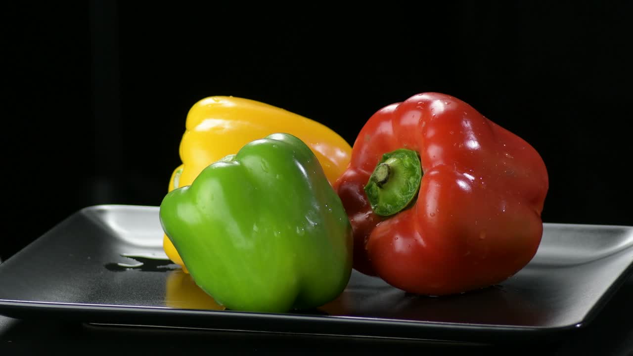 pimientos verduras amarillas, rojas y verdes girando en una bandeja negra