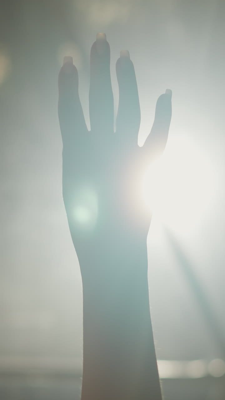 Woman fist plays silhouette at backlight closeup. Lady hand demonstrates protest gesture against glowing lamp in darkness. Activism movement symbol