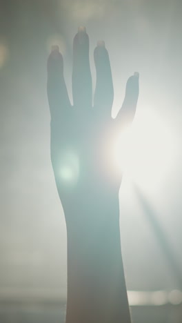 woman fist plays silhouette at backlight closeup. lady hand demonstrates protest gesture against glowing lamp in darkness. activism movement symbol